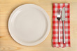 © 8th - Empty plate with cutlery on red napkin on wooden background.