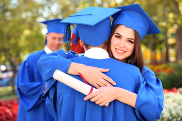 Wall Mural - Graduate students wearing graduation hat and gown, outdoors