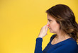 Bad smell woman covers pinches her nose yellow background 