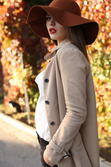 Wall Mural - beautiful ladylike woman wearing elegant clothes posing in park