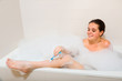 Woman shaving legs in bath