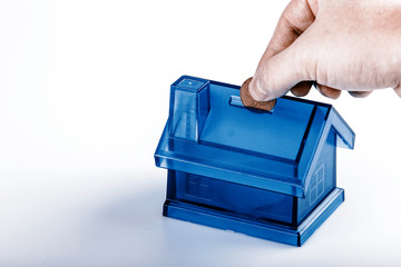 Blue House Money Box with man hand and coin on White Background