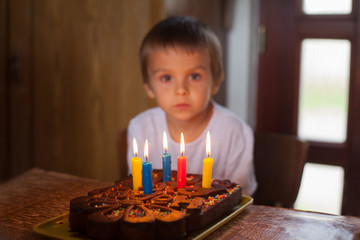 Wall Mural - Adorable five year old boy celebrating his birthday and blowing