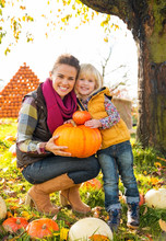 Portrait Of Happy Mother And Child Holding Pumpkin