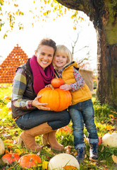 Wall Mural - Portrait of happy mother and child holding pumpkin