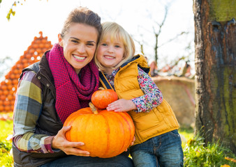 Wall Mural - Portrait of happy mother and child holding pumpkin