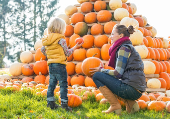 Wall Mural - Happy mother and child choosing pumpkins