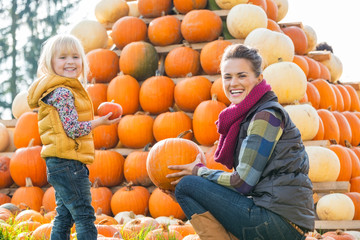 Wall Mural - Portrait of happy mother and child choosing pumpkins