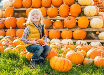 Wall Mural - Portrait of happy child sitting on pumpkin
