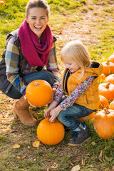 Wall Mural - Smiling mother and child choosing pumpkins