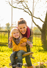 Wall Mural - Portrait of smiling mother and child on swing