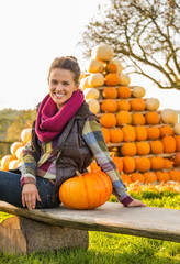 Wall Mural - Portrait of happy young woman sitting with pumpkin 