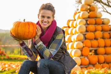 Wall Mural - Portrait of happy young woman sitting with pumpkin 