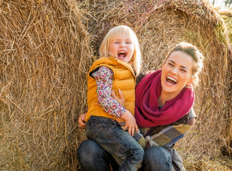 Wall Mural - Portrait of smiling mother and child near haystack