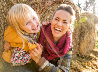 Wall Mural - Portrait of smiling mother and child near haystack