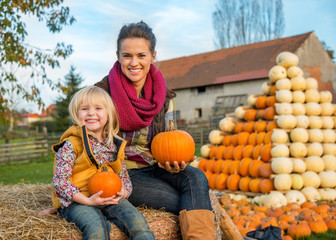 Wall Mural - Portrait of happy mother and child sitting on haystack 