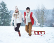 canvas print picture - Glückliches Paar zieht Schlitten im Schnee