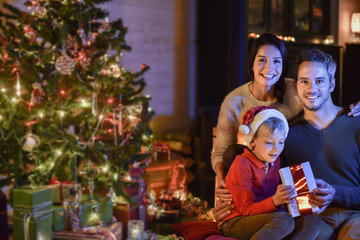 Wall Mural - lovely family opening a gift on Christmas night near the wood st