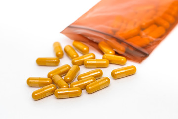 Drug capsules in plastic container on white background