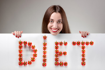 Woman pointing on white billboard over grey background in studio