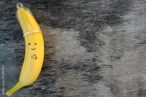 Naklejka - mata magnetyczna na lodówkę Banana with condom on the old wooden background.