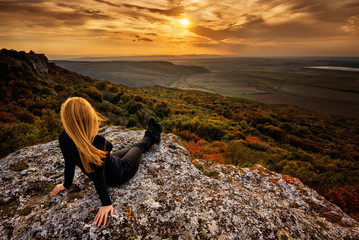 Wall Mural - a woman enjoys the view of sunset over an autumn forest