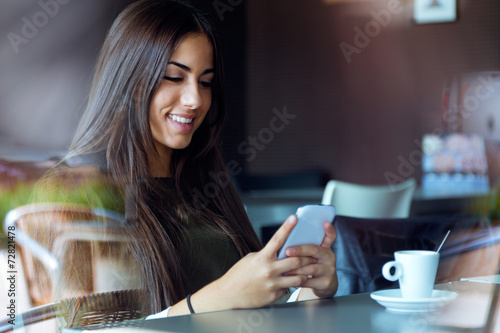 Fotografie, Obraz Beautiful girl using her mobile phone in cafe.