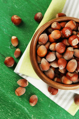 Wall Mural - Hazelnuts in wooden bowl, on napkin on wooden background