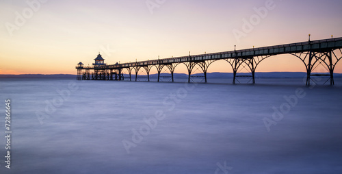 Plakat na papierze fotorealistycznym Piękny długi zachód słońca nad ocean z sylwetka molo