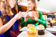 Frauen essen Muffins beim Kaffee trinken