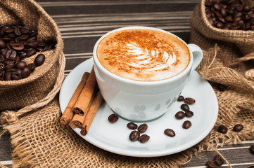 Cappuccino in a white cup with cinnamon and drawing on milk