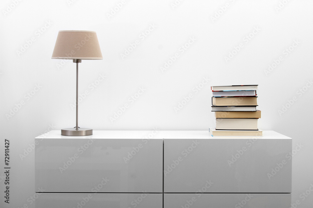 white commode with lamp and books in bright minimalism interior - obrazy, fototapety, plakaty 