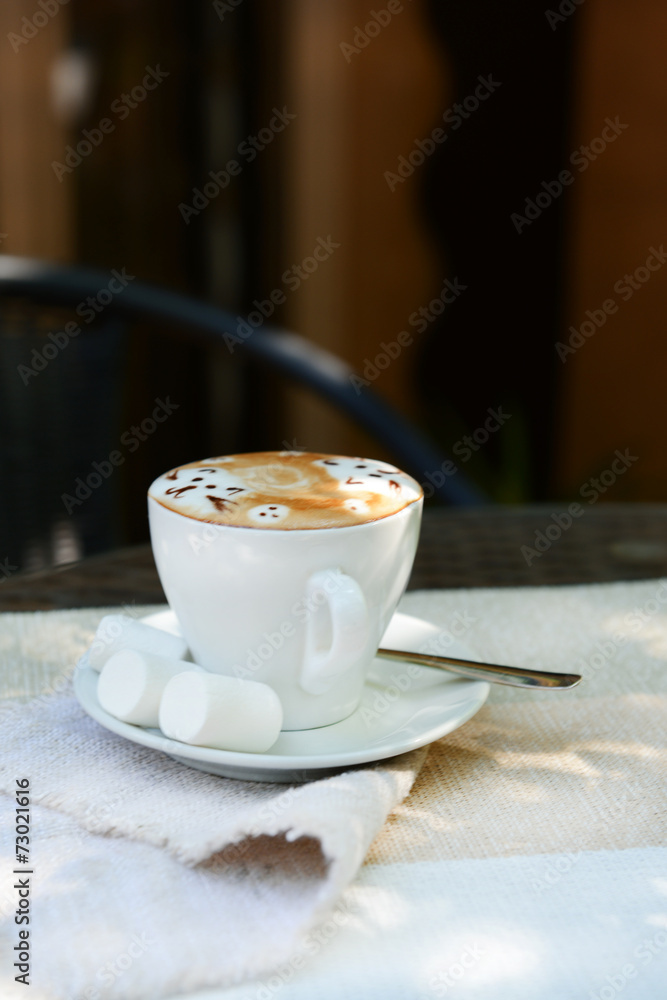 Cup of coffee with cute drawing on table, close up