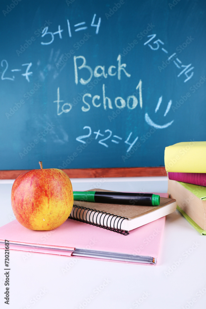 School supplies on table on blackboard background