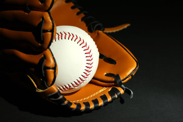 Baseball ball in glove on black background