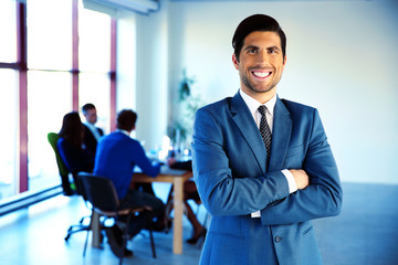 Poster - Cheerful businessman standing with arms folded