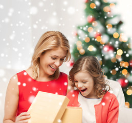 Canvas Print - smiling mother and daughter with gift box at home