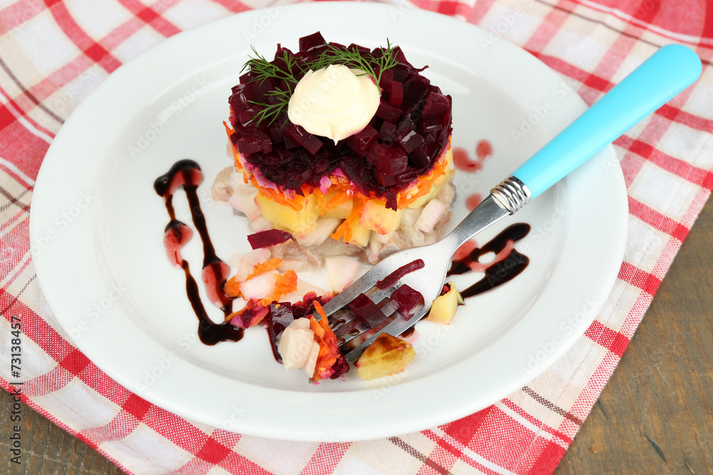 Russian herring salad on plate on wooden table background
