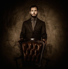 Wall Mural - Handsome well-dressed  standing near leather chair