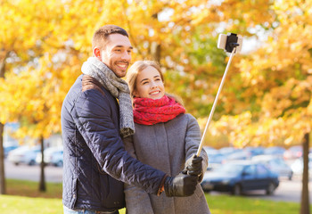 Wall Mural - smiling couple with smartphone in autumn park