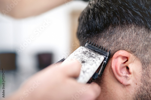 Fotomural men's hairstyling and haircutting with hair clipper in a barber