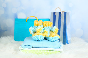 Wall Mural - Baby clothes and gift bag on bright background