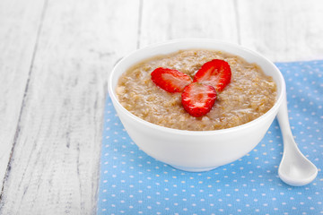 Wall Mural - Tasty oatmeal with strawberry on table close-up