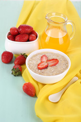 Wall Mural - Tasty oatmeal with strawberry and juice on table close-up