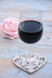 glas rode wijn op houten tafel met hart decoratie en roze roosje