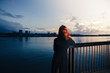 © LoloStock - Woman admiring sunset over river in city