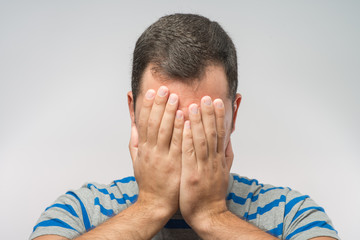 Young Caucasian man hiding his face with hand