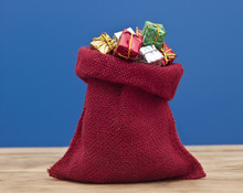 Colorful Gift Boxes With Ribbons And Bows, And Red Sack On Woode