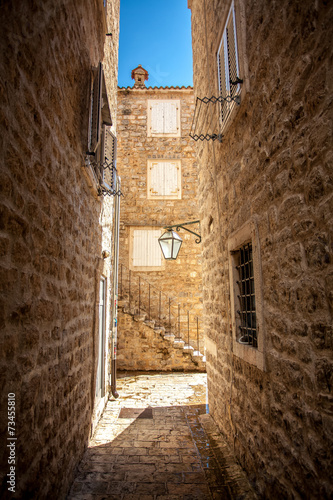 Fototapeta na wymiar old narrow street with high buildings at sunny day