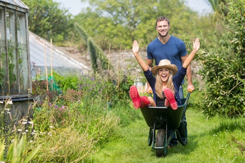 Fotografía Man pushing his girlfriend in a wheelbarrow